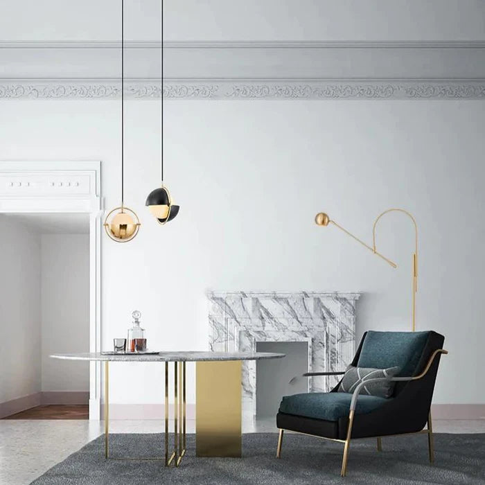 Gold metal hanging and standing lights beside a table and black sofa chair